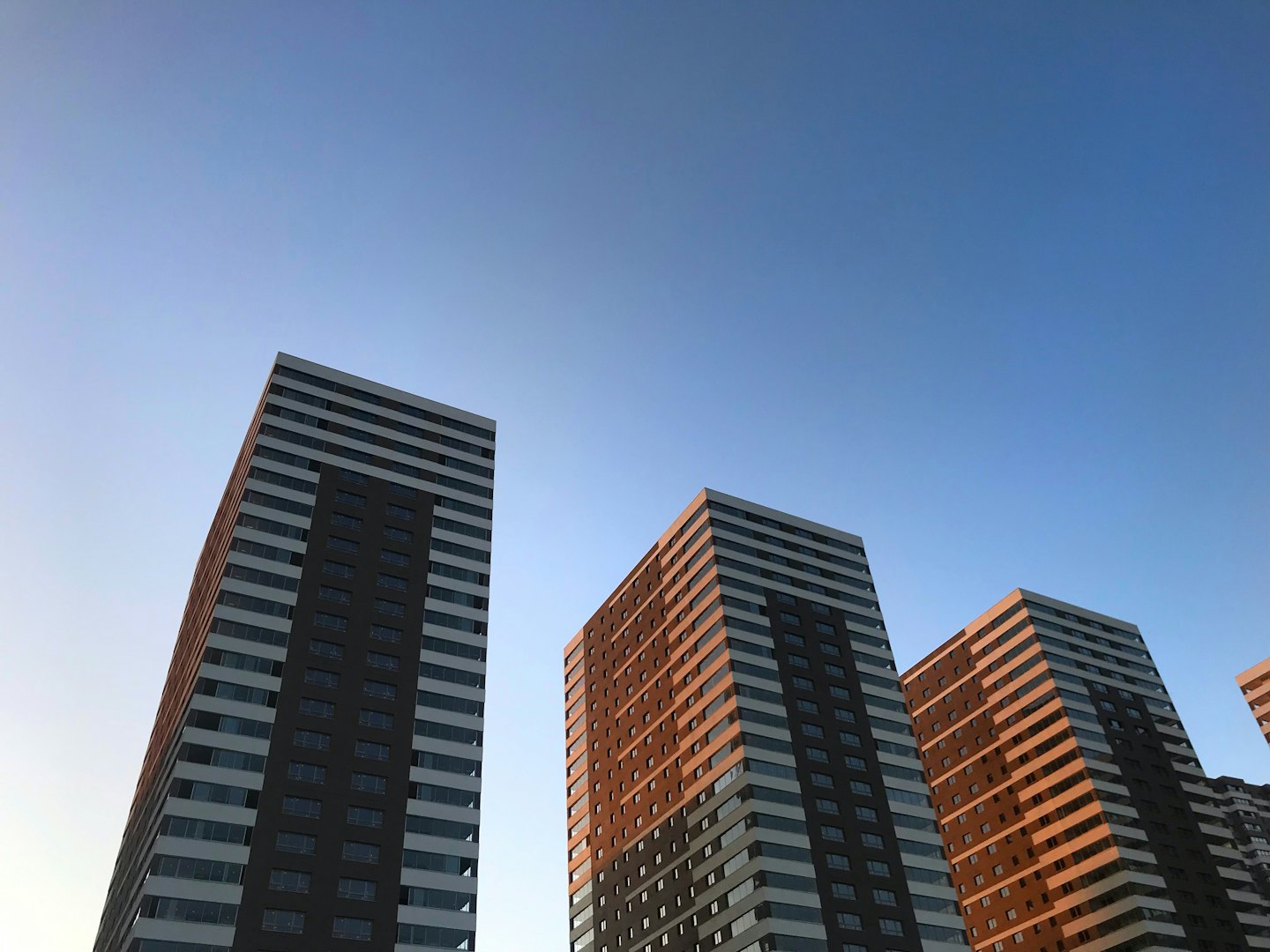 Modern high-rise residential buildings reach toward a clear blue sky.